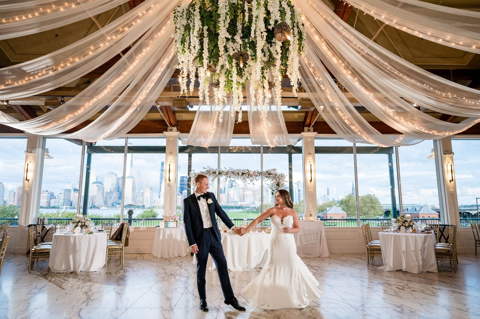 A bride and groom dance in a large ballroom with a chandelier at Liberty House in Jersey City NJ