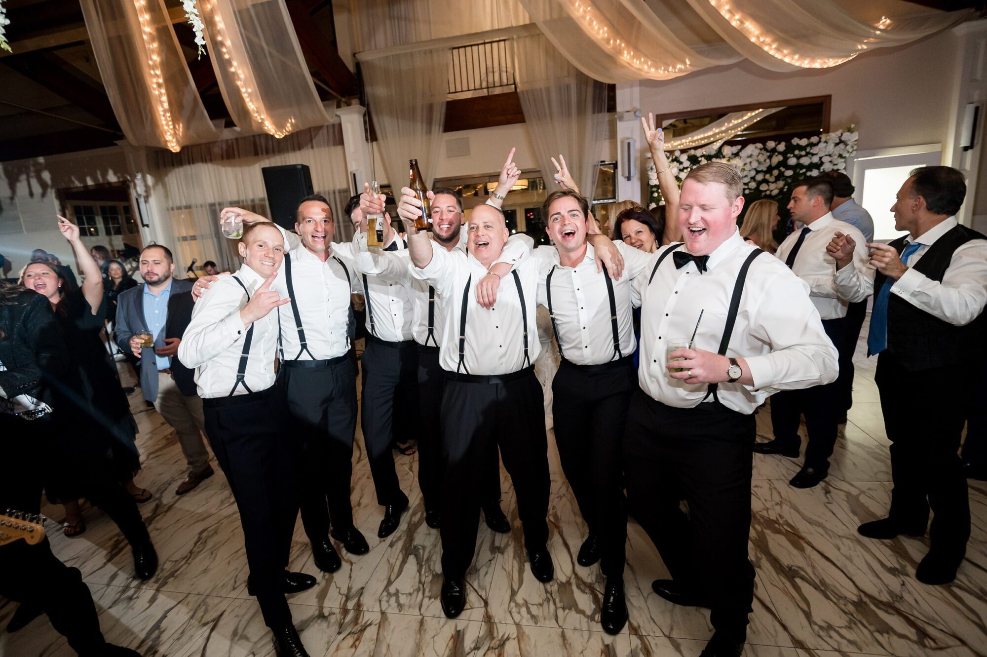 A group of men in tuxedos dancing at a wedding reception.