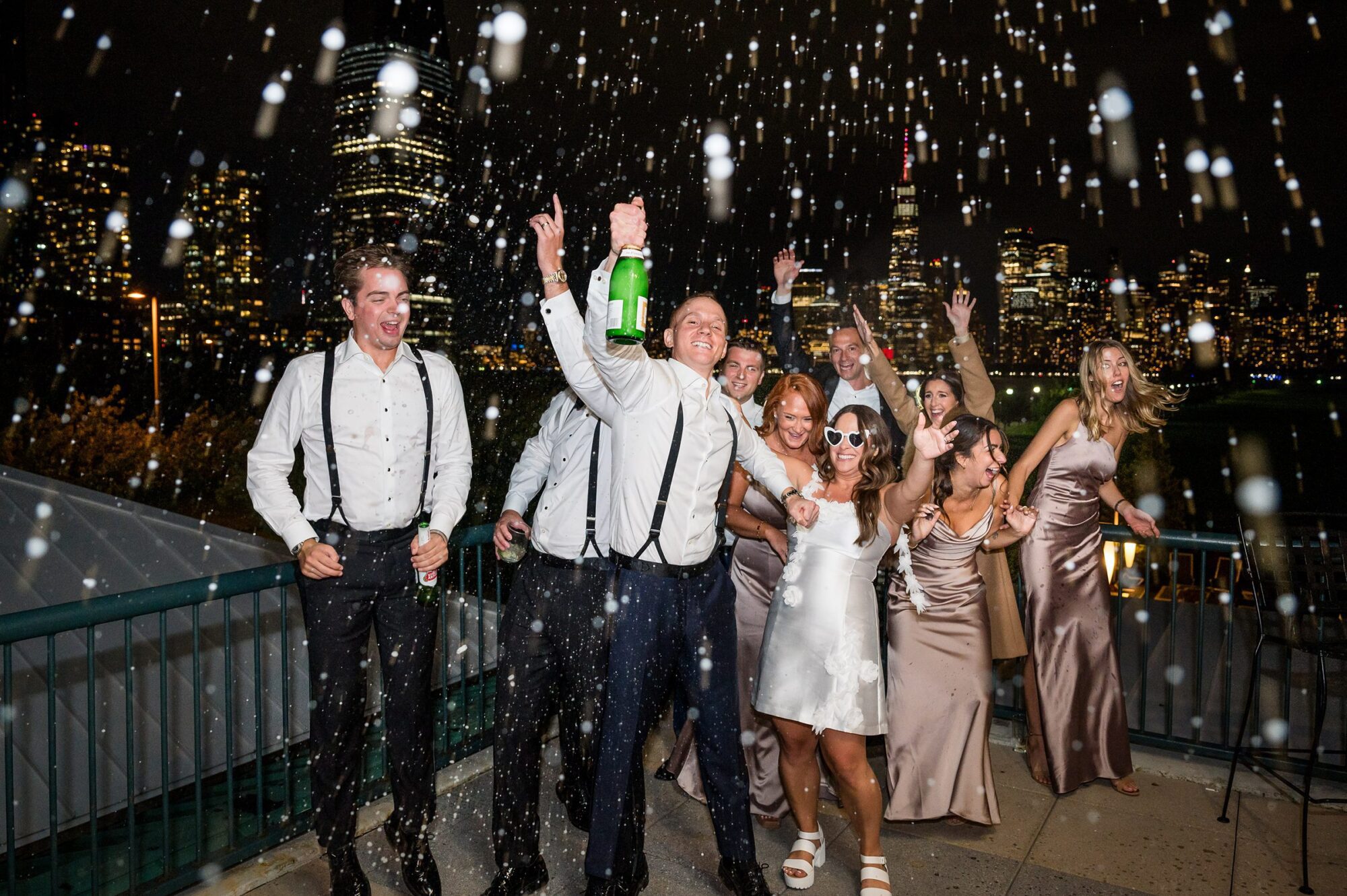 A group of bridesmaids and groomsmen spraying champagne at a Liberty House wedding in Jersey City NJ