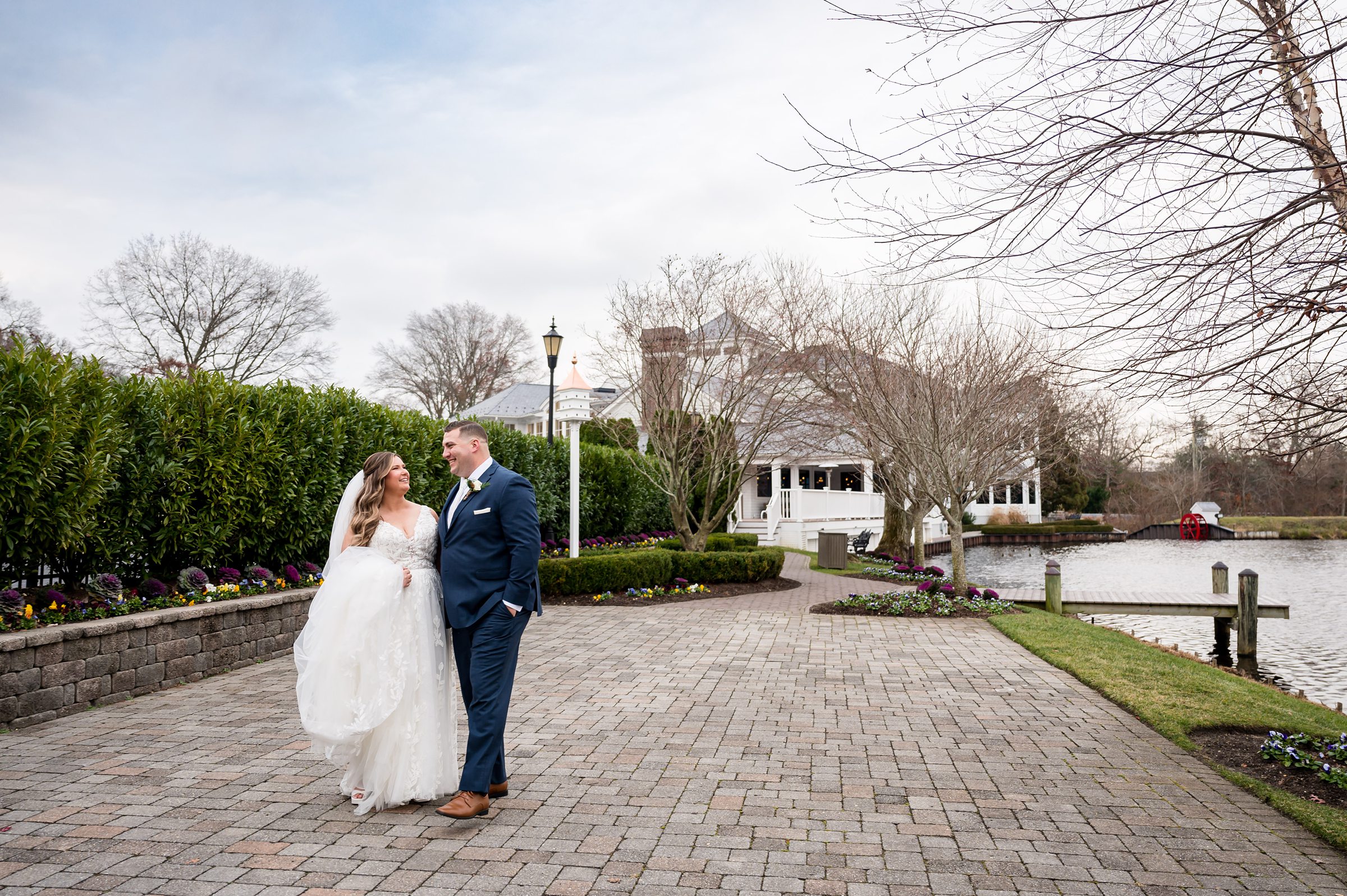 A bride and groom standing in front of The Mill Lakeside Manor by a lake