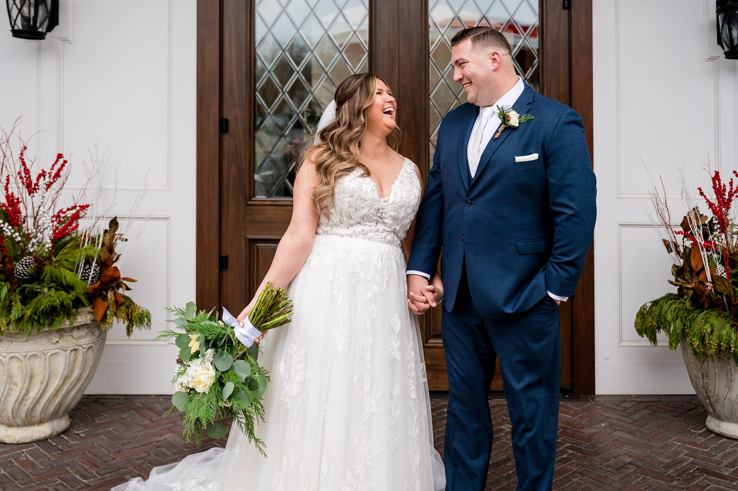 A bride and groom smiling in front of a door.